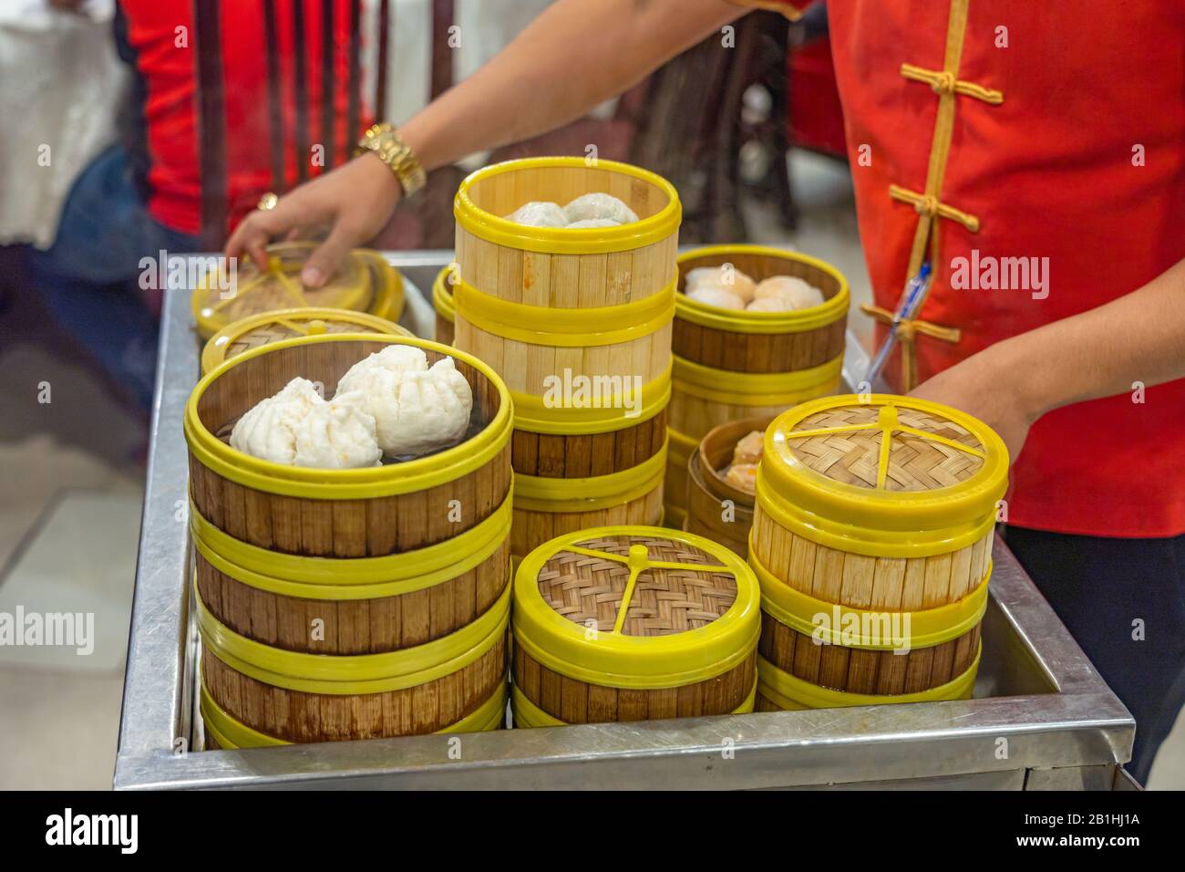 Cameriera che serve dimmsum al vapore sul carrello in ristorante cinese Foto Stock
