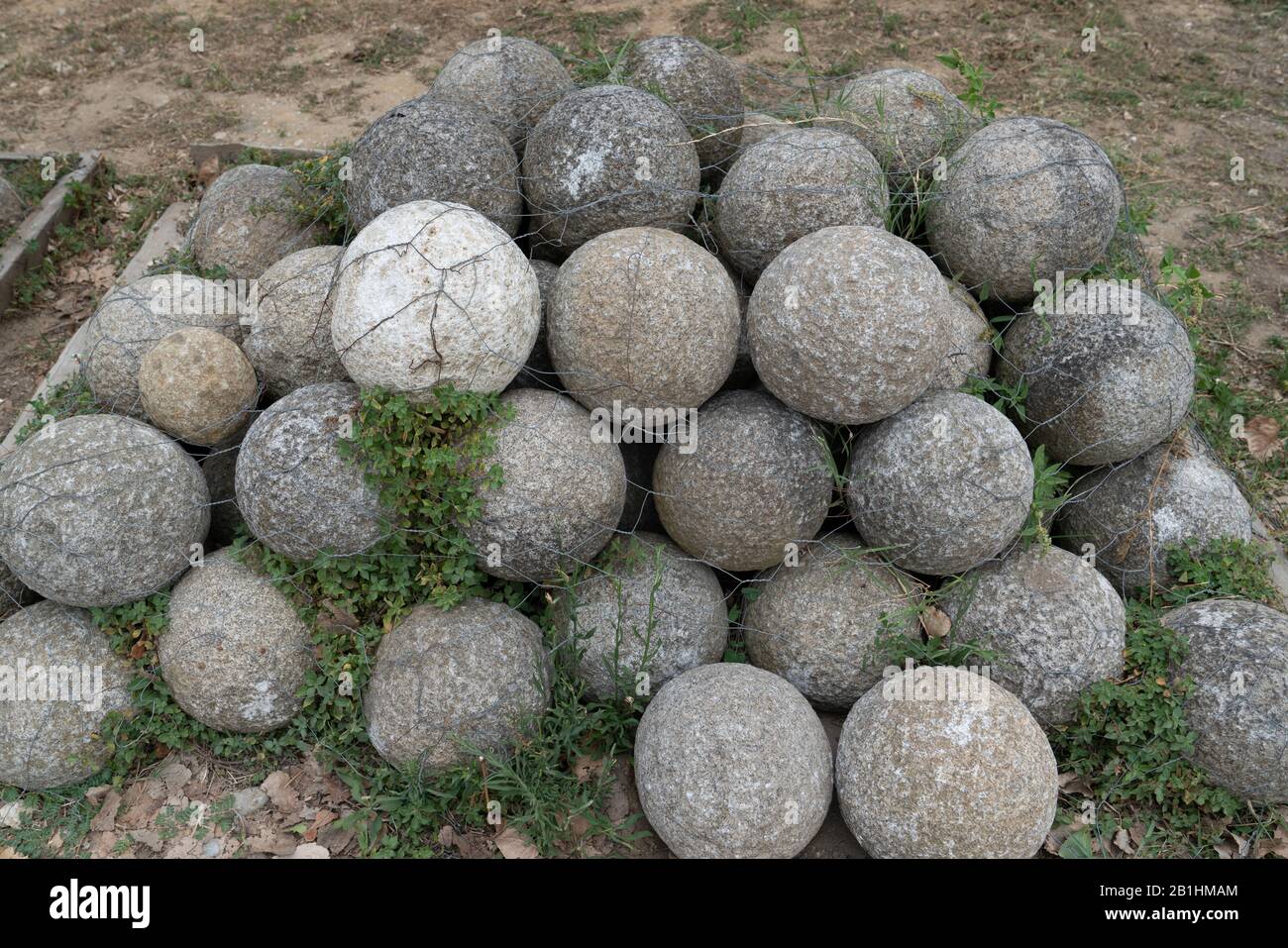 Nuclei di pietra rotondi per un'antica catapulta impilati in una piramide Foto Stock