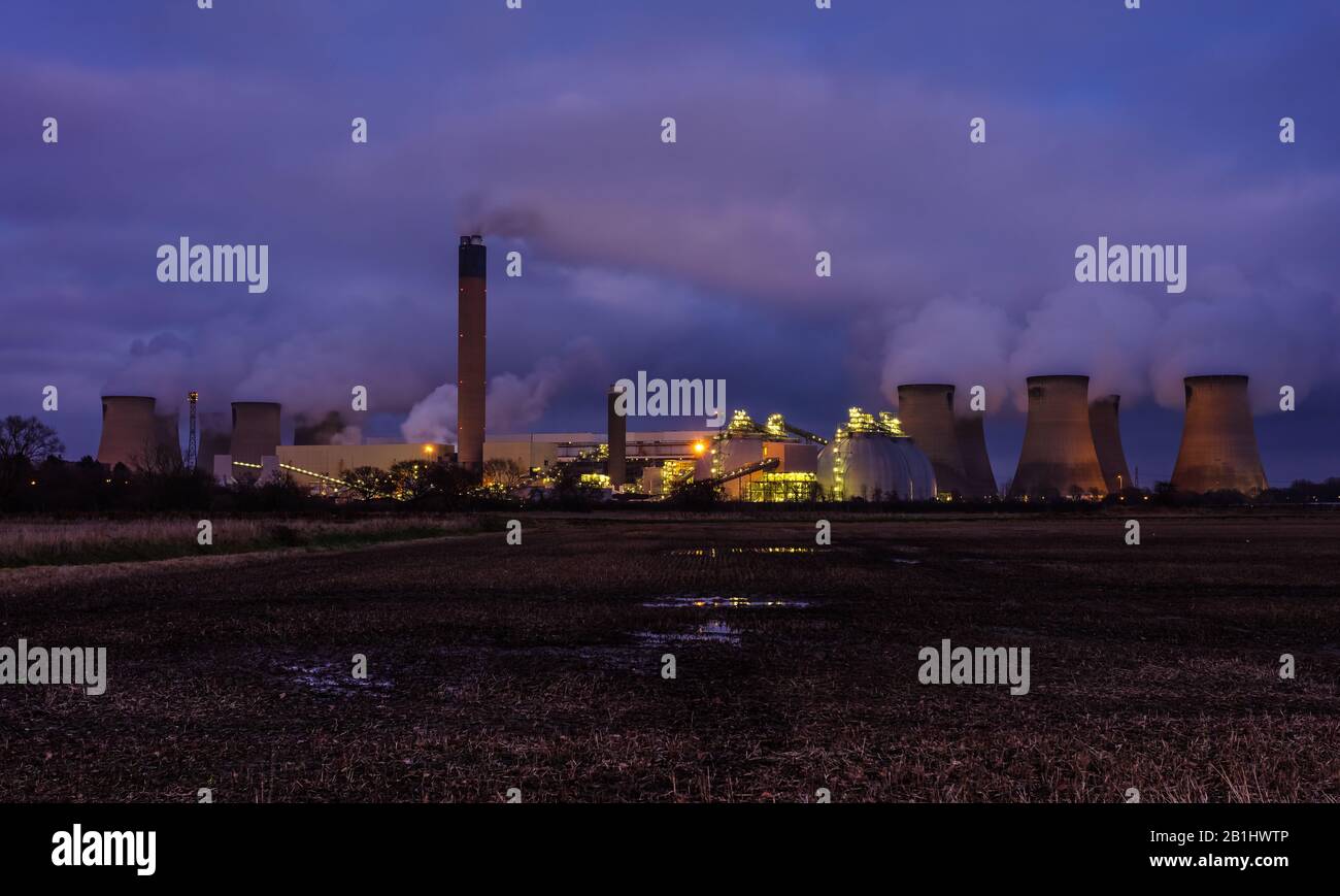Drax, North Yorkshire. La sera cade sul villaggio rurale di Drax con le luci scintillanti di una centrale elettrica locale e il vapore acqueo che emette dal Th Foto Stock