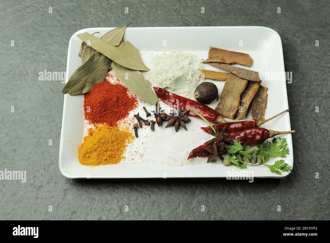 Spezie indiane come foglie di alloro, peperoncini in polvere, curcuma in un piatto Foto Stock
