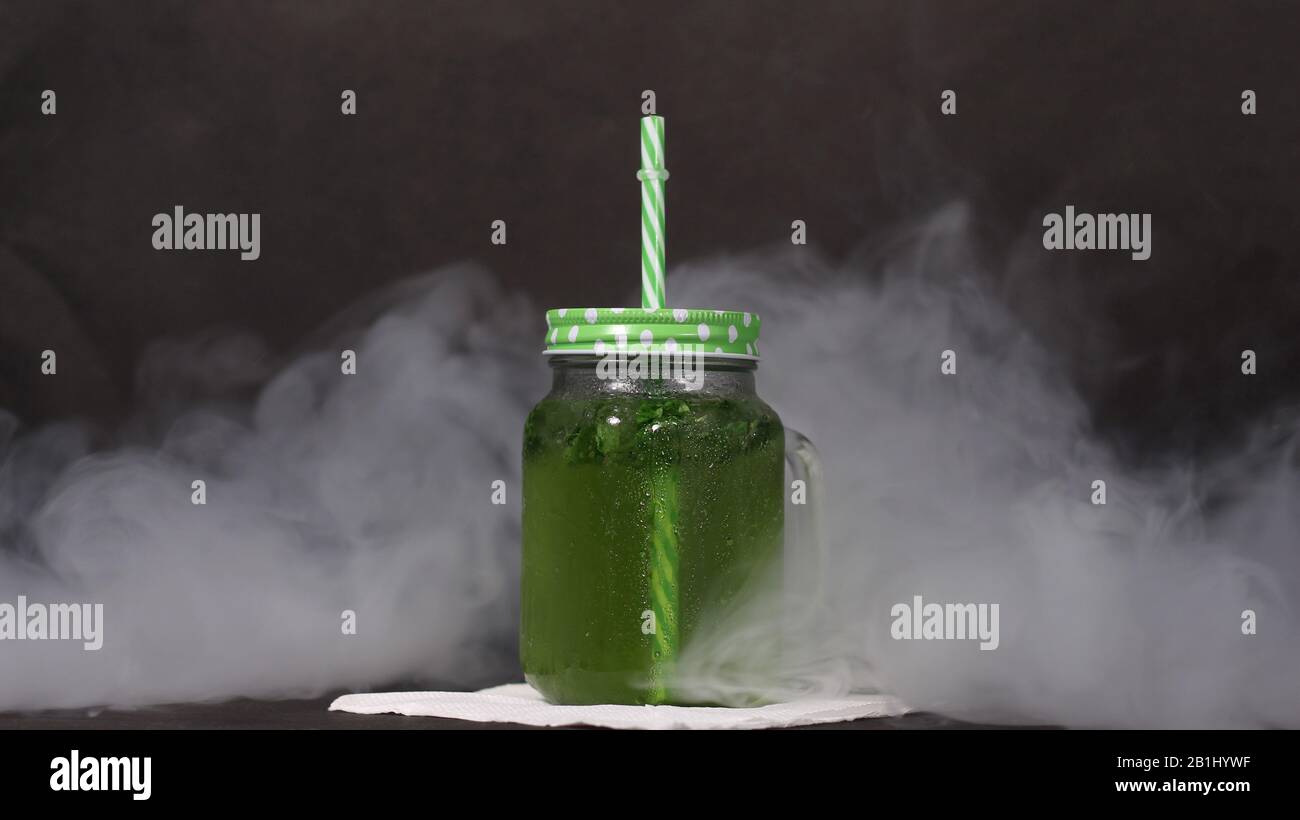 Dea verde mocktail in vaso muratore con paglia e sfondo fumoso Foto Stock