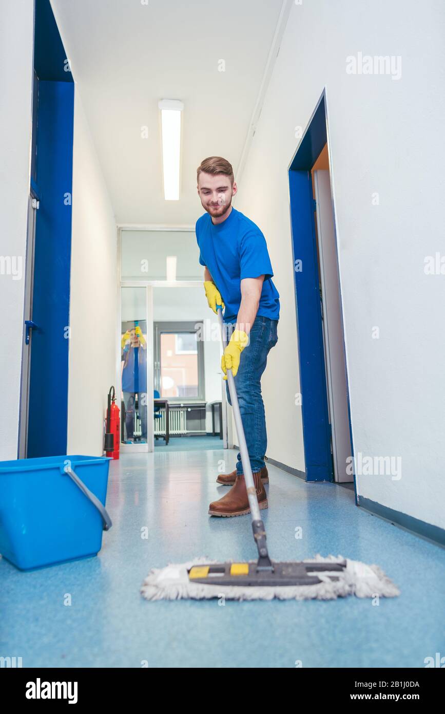 Un uomo più pulito che pulisci il pavimento in una hall Foto stock - Alamy