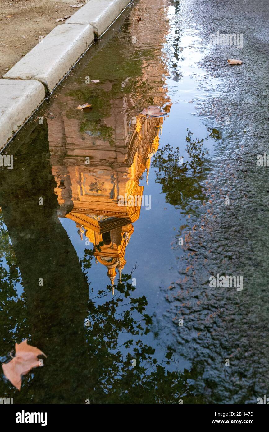 Un edificio in Plaza de Espana che riflette in una piccola pozza sulla strada a Siviglia, Andalusia, Spagna. Foto Stock