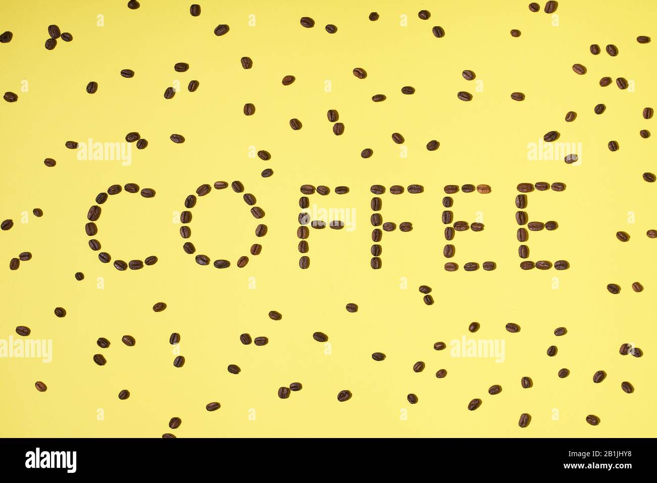 Caffè a base di chicchi di caffè arabica tostati freschi su sfondo giallo. Disposizione piatta minima creativa Foto Stock