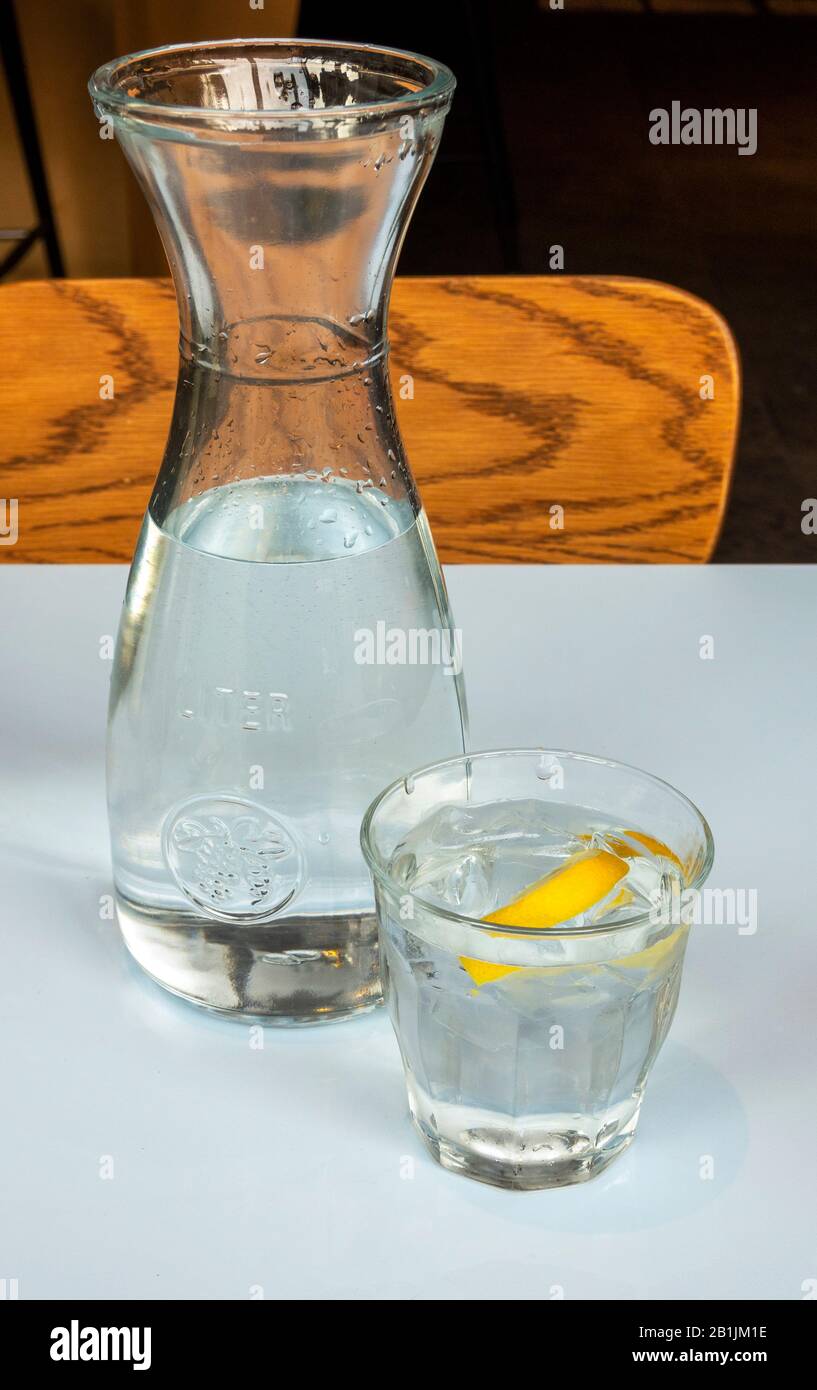 Una bottiglia d'acqua da 1 litro e un bicchiere con un cuneo di limone e ghiaccio Foto Stock
