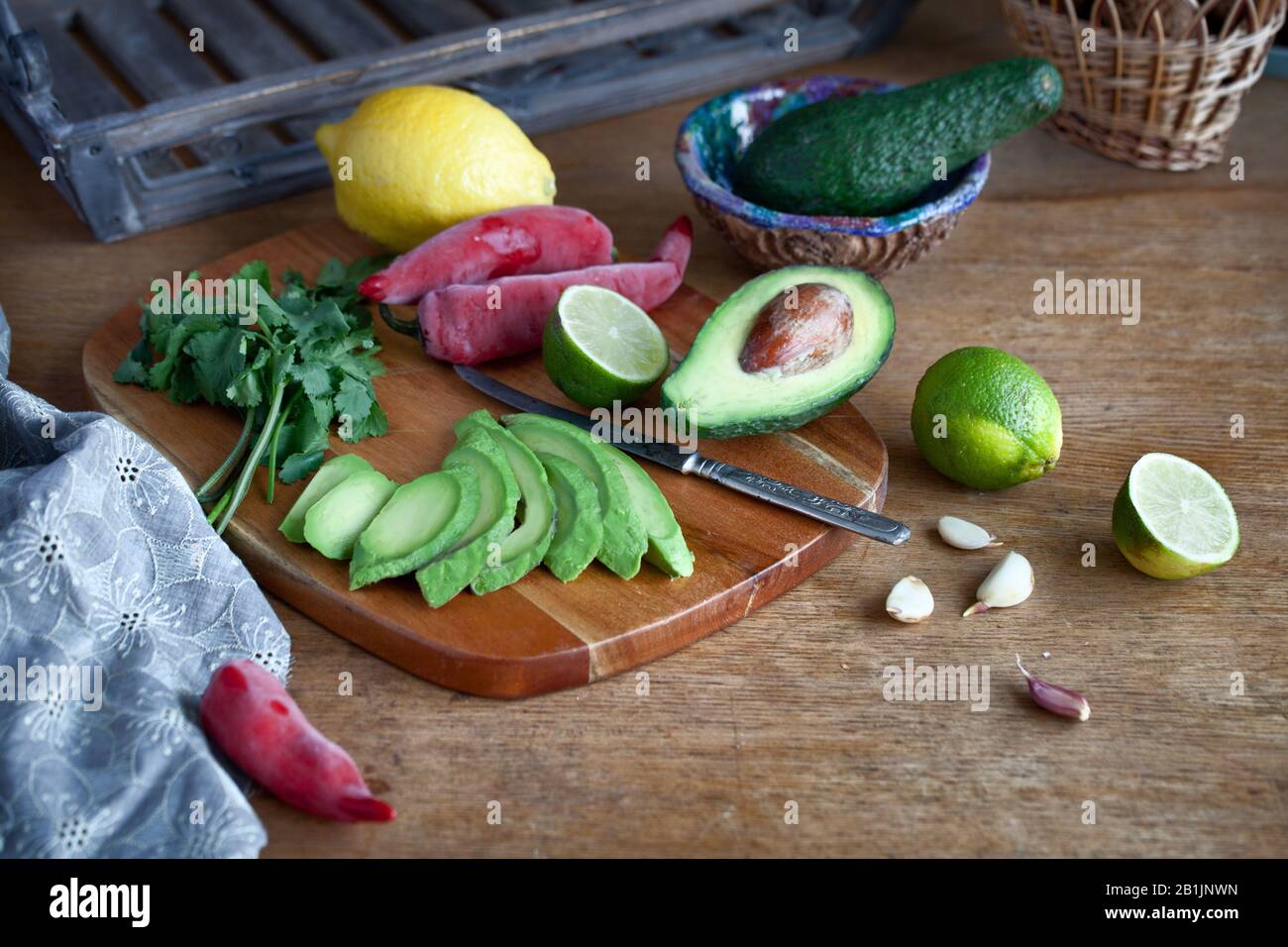 La cottura di cibo messicano guacamole - avocado, calce, limone e pepe, aglio e coriandolo su una tavola di legno. cibo sfondo con spazio di copia Foto Stock