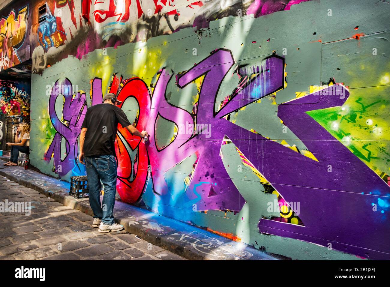 Young man spray pittura graffiti muro, Hosier Street, Melbourne Lanes, Melbourne, Victoria, Australia Foto Stock