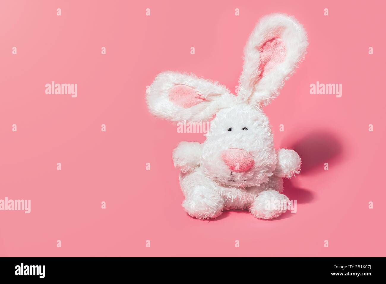 Adorabile coniglio farcito su sfondo rosa con spazio copia. Concetto di Pasqua minimo. Foto Stock