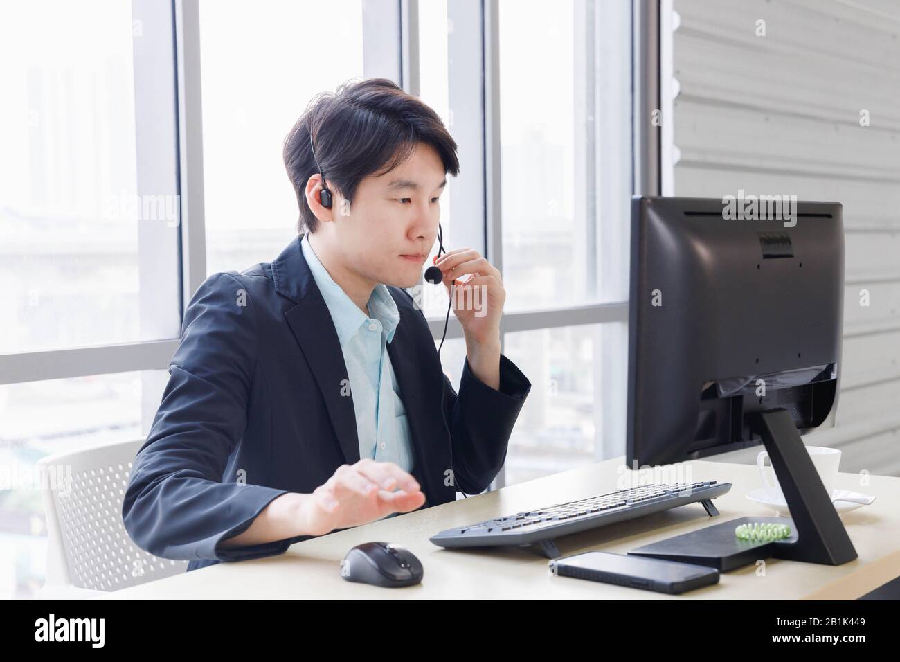 L'operatore del call center asiatico lavora in ufficio e parla con il cliente. Concetto di servizio di assistenza clienti, stile di vita in ufficio, dipendente. Foto Stock