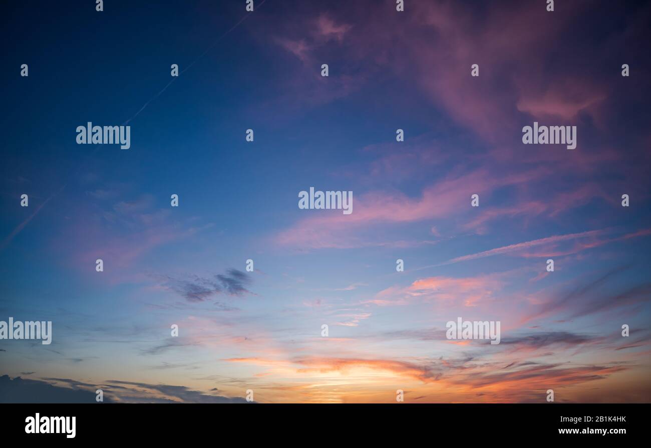Cielo blu durante l'alba con nuvole sparse viola durante un tramonto Foto Stock