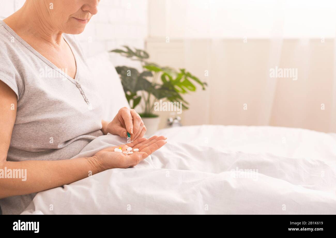 Donna anziana che prende ogni giorno il farmaco a letto Foto Stock