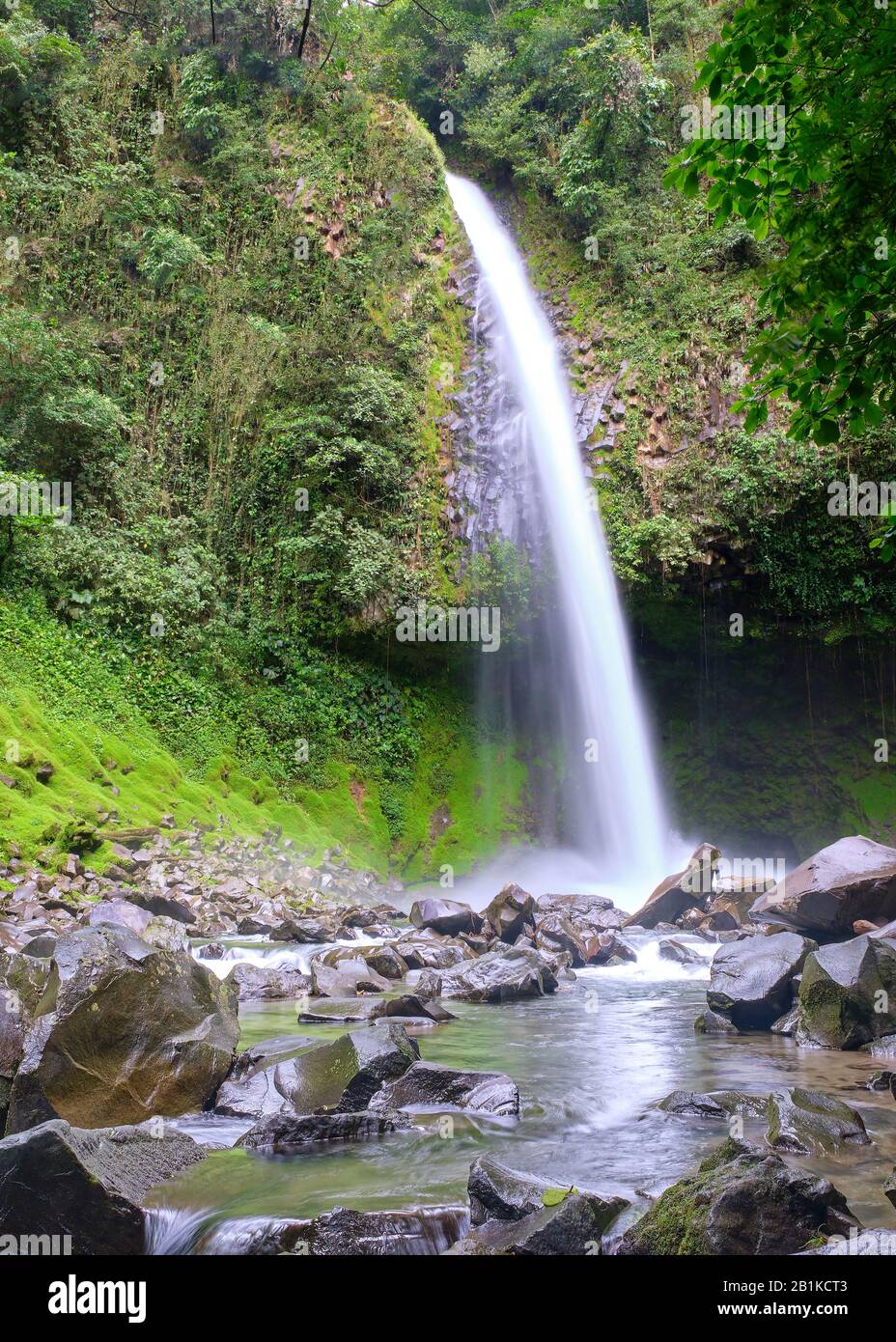 La cascata di Fortuna, alta 70 metri, in Costa Rica, si vedeva guardando il torrente verso le cascate, con rocce e una piccola piscina d'acqua nel terreno. Foto Stock