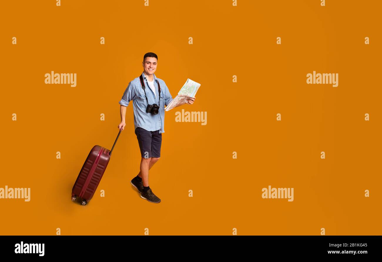 Turistico con bagaglio che tiene la mappa, andando verso lo spazio copia Foto Stock