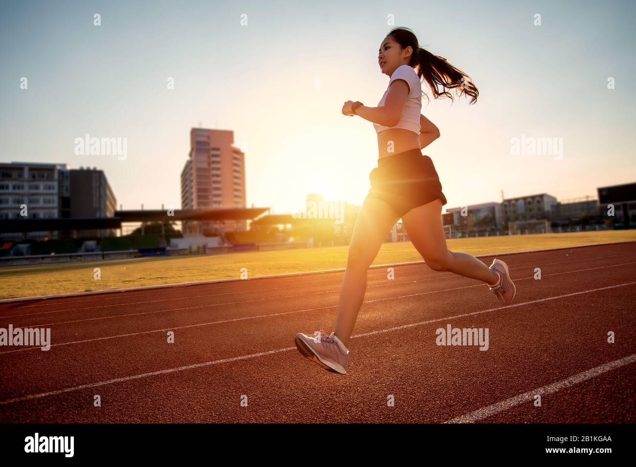 Asian Young fitness woman runner in corsa sulla pista dello stadio Foto Stock