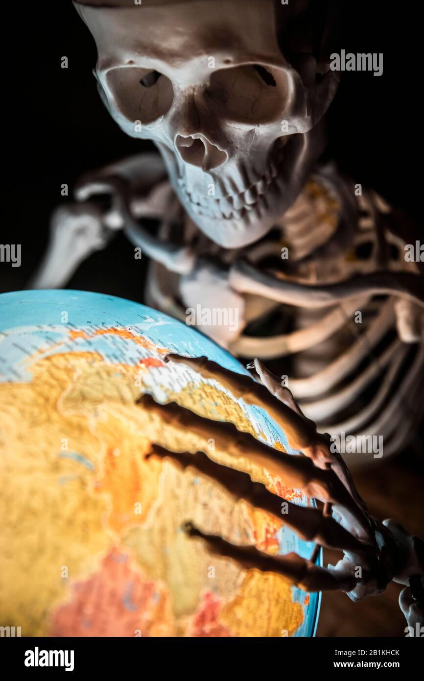 Scheletro con mano ossea su globo, immagine simbolica di guerra e catastrofe ambientale, la Germania Foto Stock