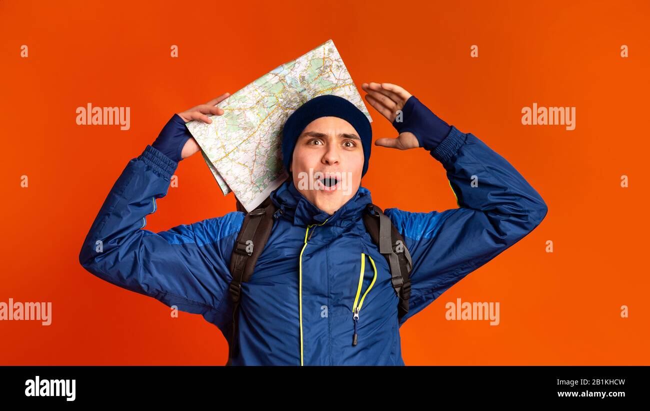 Il viaggiatore impressionato con la mappa della città sopra lo sfondo arancione dello studio Foto Stock