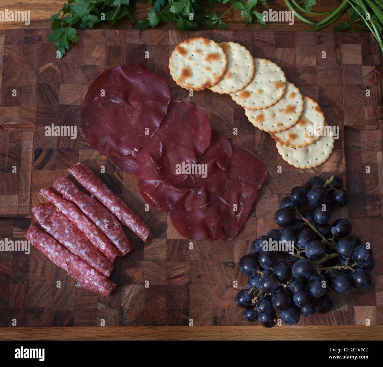 Una selezione di salumi italiani, uva, cracker ed erbe fresche Foto Stock