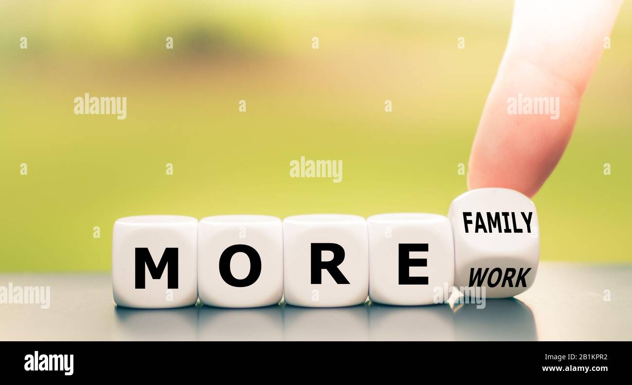 Il dito gira i dadi e cambia l'espressione "più lavoro" in "più famiglia". Foto Stock