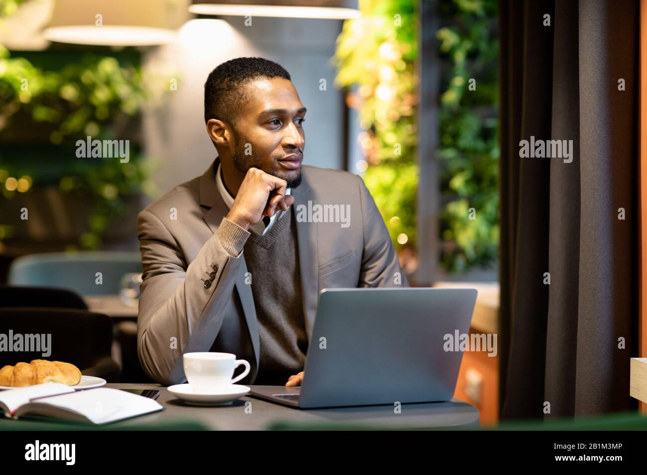 Direttore Afro che guarda fuori dalla finestra nel caffè Foto Stock