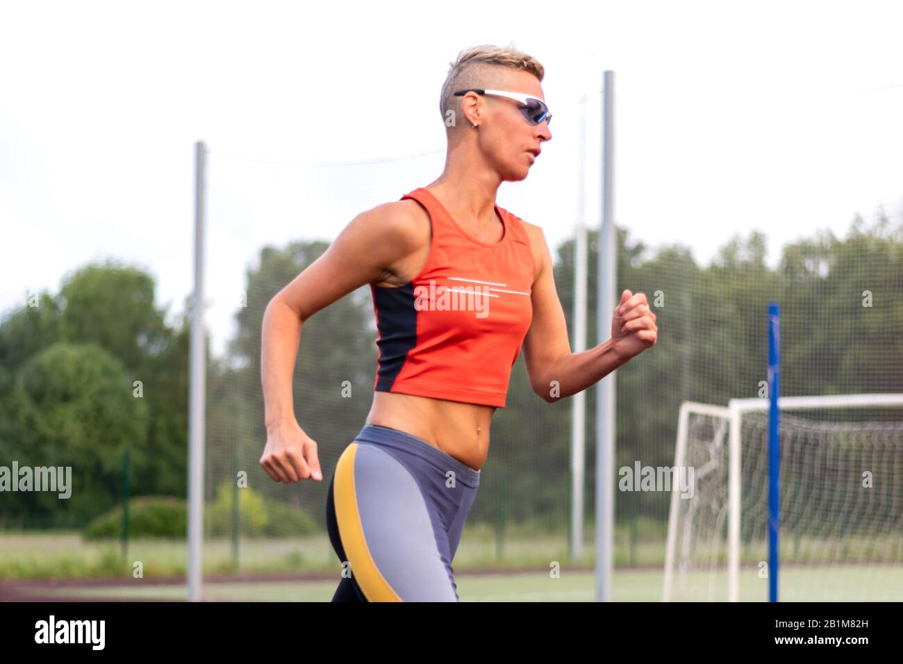 Una donna adulta corre allo stadio, in abiti sportivi. Foto Stock