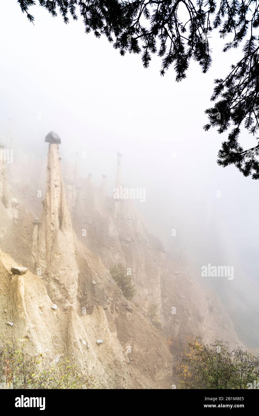 Cielo nebbioso in autunno sulle formazioni rocciose delle Piramidi della Terra, Perca/Percha, provincia di Bolzano, Alto Adige, Italia Foto Stock