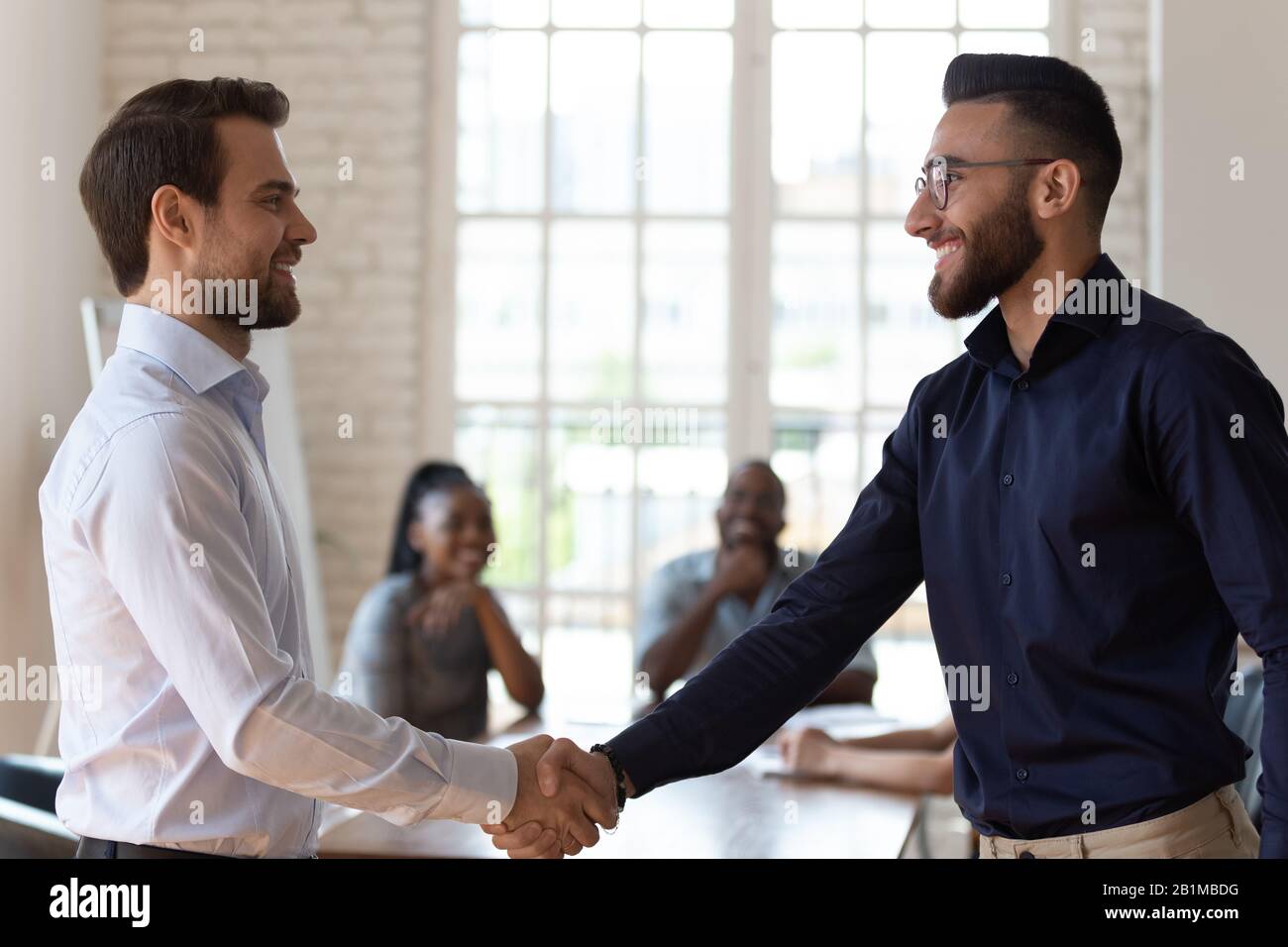 Caucasico e medio-orientale etnia uomo d'affari handshaking salutarsi l'un l'altro Foto Stock