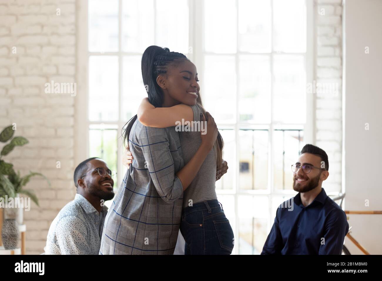 Psicologo donna africana che abbraccia la ragazza alla sessione di terapia di gruppo Foto Stock