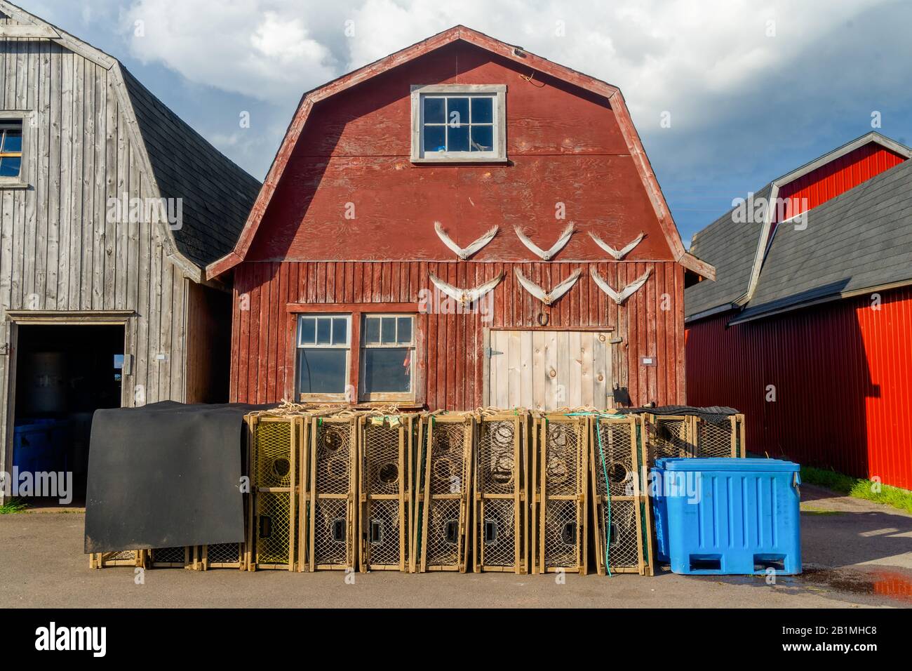 Trappole di aragosta accatastate contro i capannoni di esche su un molo nella rurale Prince Edward Island, Canada, Foto Stock