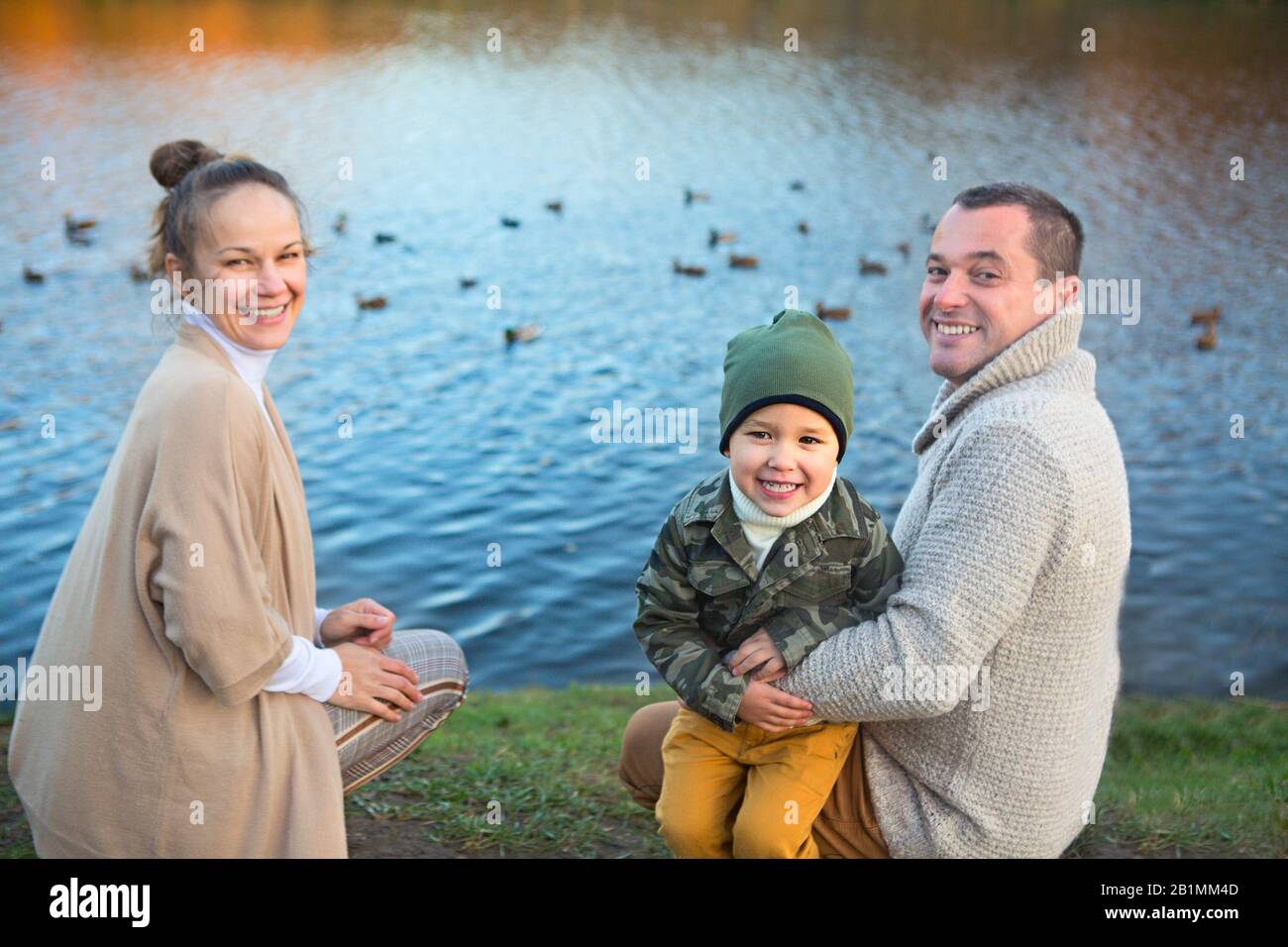 Padre, Madre e piccolo figlio di anatre di alimentazione dal lago in autunno Foto Stock