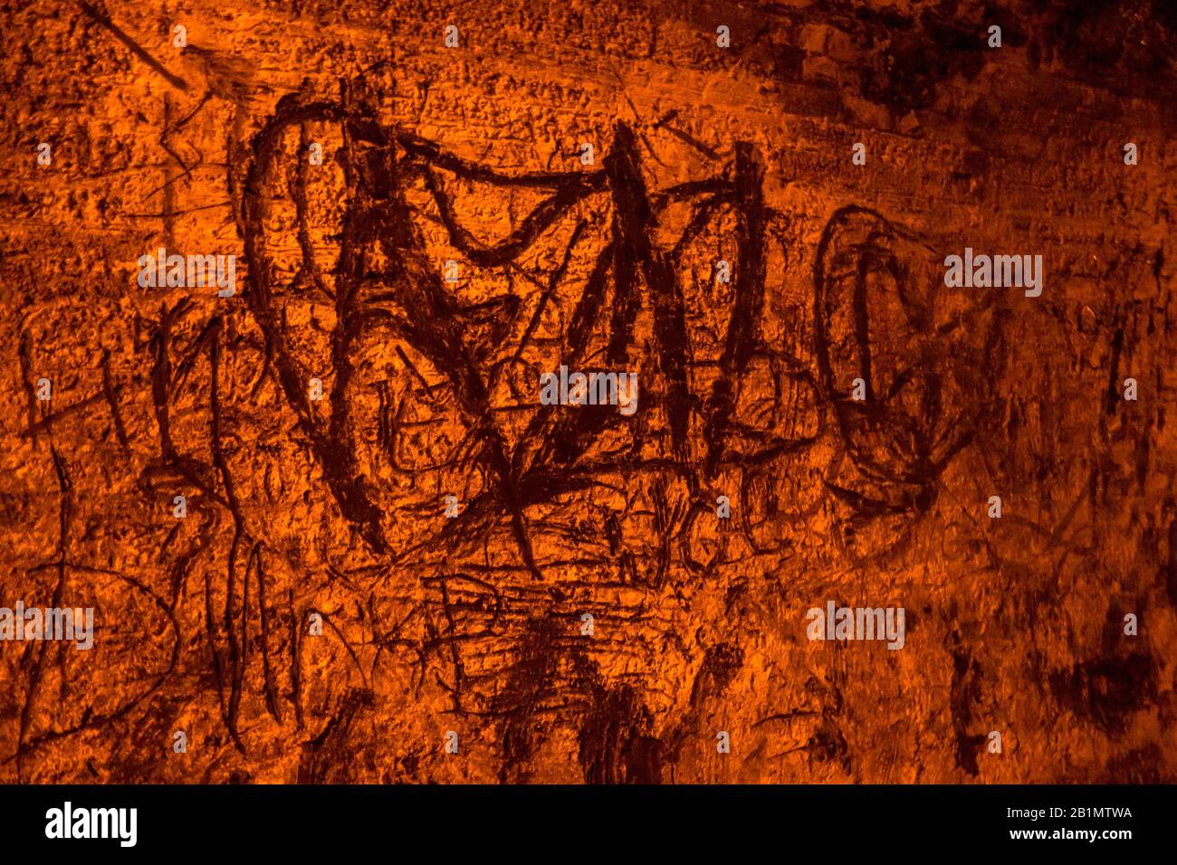 Misteriosi simboli sulla parete all'interno del tunnel di Karangahake, Nuova Zelanda. La luce rossa illumina la scena. Foto di scorta gratuita. Foto Stock
