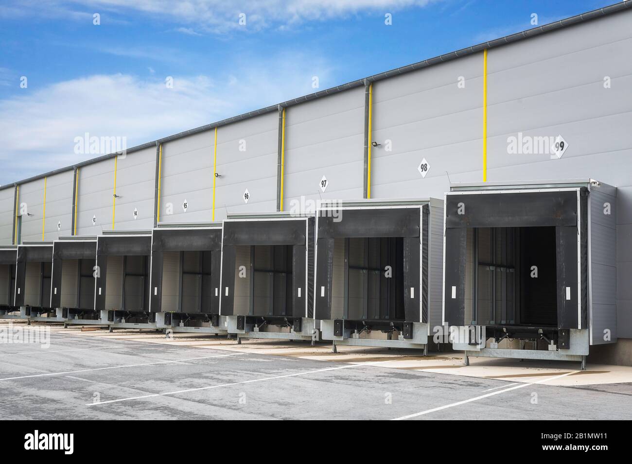 Banchine di carico magazzino in una giornata di sole. Cancelli aperti di un magazzino industriale. Porte Storehouse in una fila. Magazzino di distribuzione con porte aperte. Foto Stock