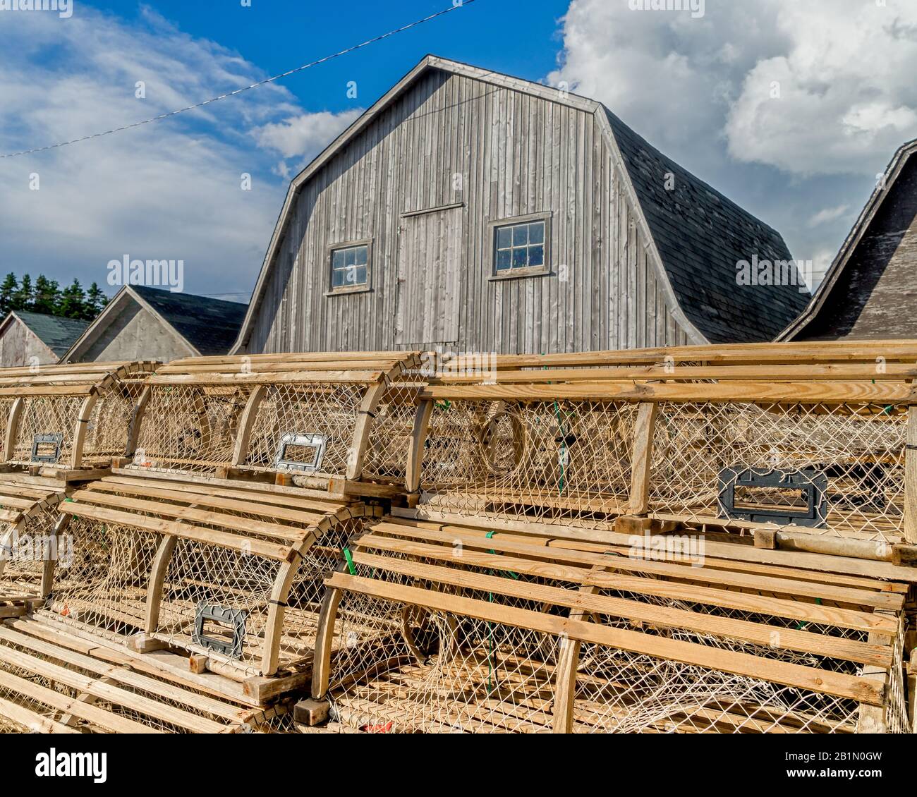 Trappole di aragosta accatastate contro i capannoni di esche su un molo nella rurale Prince Edward Island, Canada, Foto Stock