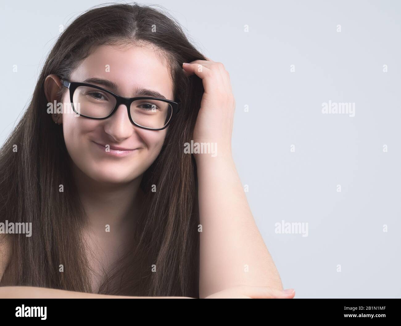 Ritratto di una Sorridente Brunette Teen Girl dai capelli lunghi Bespectacled Foto Stock