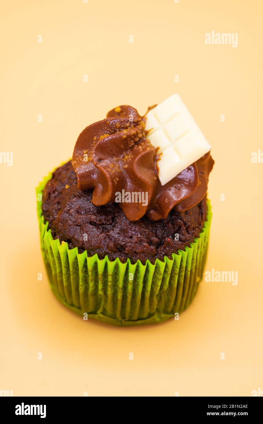 Gustoso cupcake al cioccolato su sfondo color pastello arancione. Foto Stock
