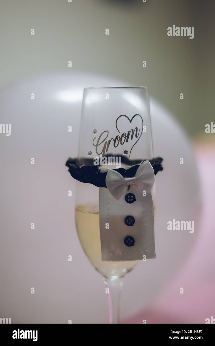 Un bicchiere di champagne di novità con un tuxedo e le parole Sposo sul bicchiere Foto Stock