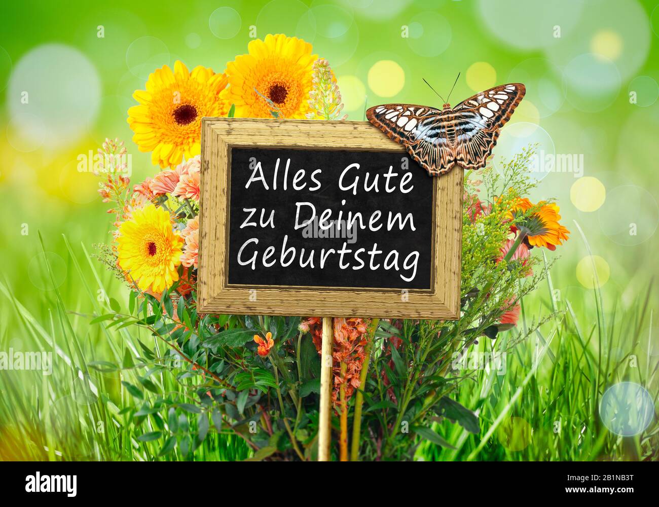 Piccola lavagna con una farfalla contro un prato fiori lettere ALLES GUTE ZUM GEBURTSTAG (buon compleanno) Foto Stock