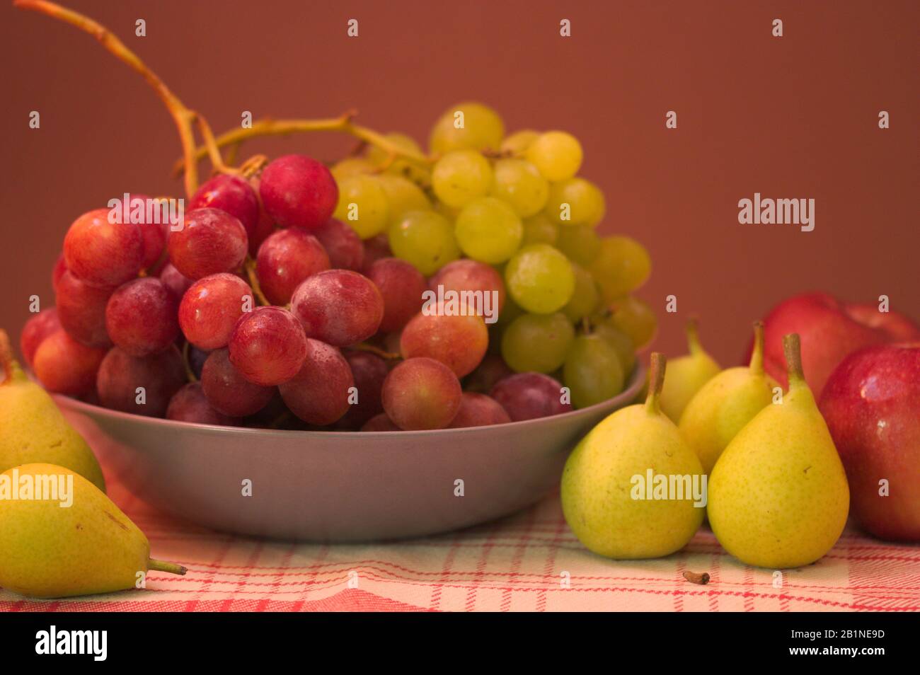 Ancora vita di frutta con uve bianche e nere, pere, mele, con sfondo marrone con spazio per i testi. Foto Stock