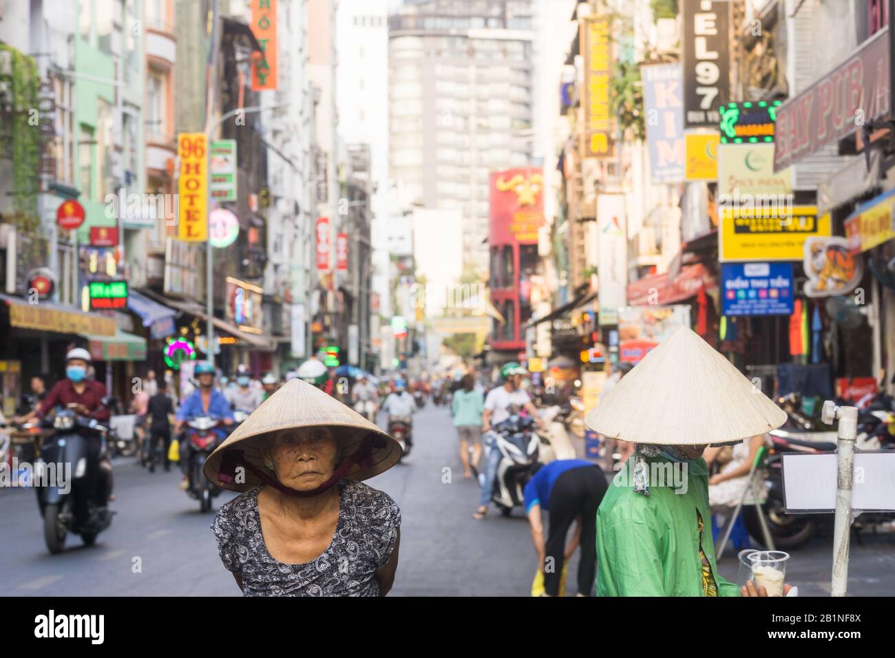 Saigon (ho Chi Minh City) strada Bui Vien - Anziana donna vietnamita con un cappello conico in una strada turistica Bui Vien a Saigon, Vietnam. Foto Stock