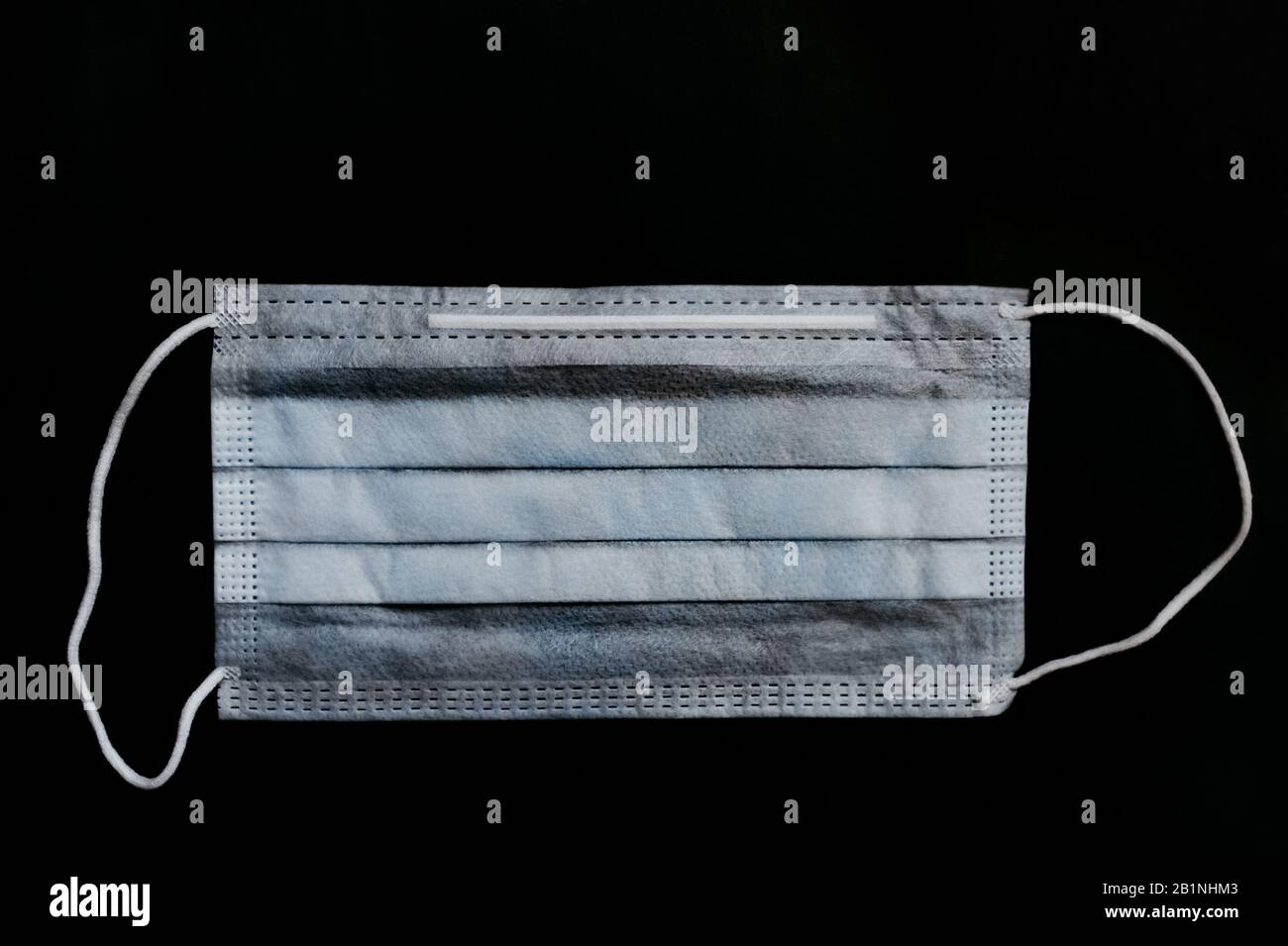 maschera medica blu con bande elastiche in tessuto su fondo nero.  disposizione piatta. vista dall'alto Foto stock - Alamy