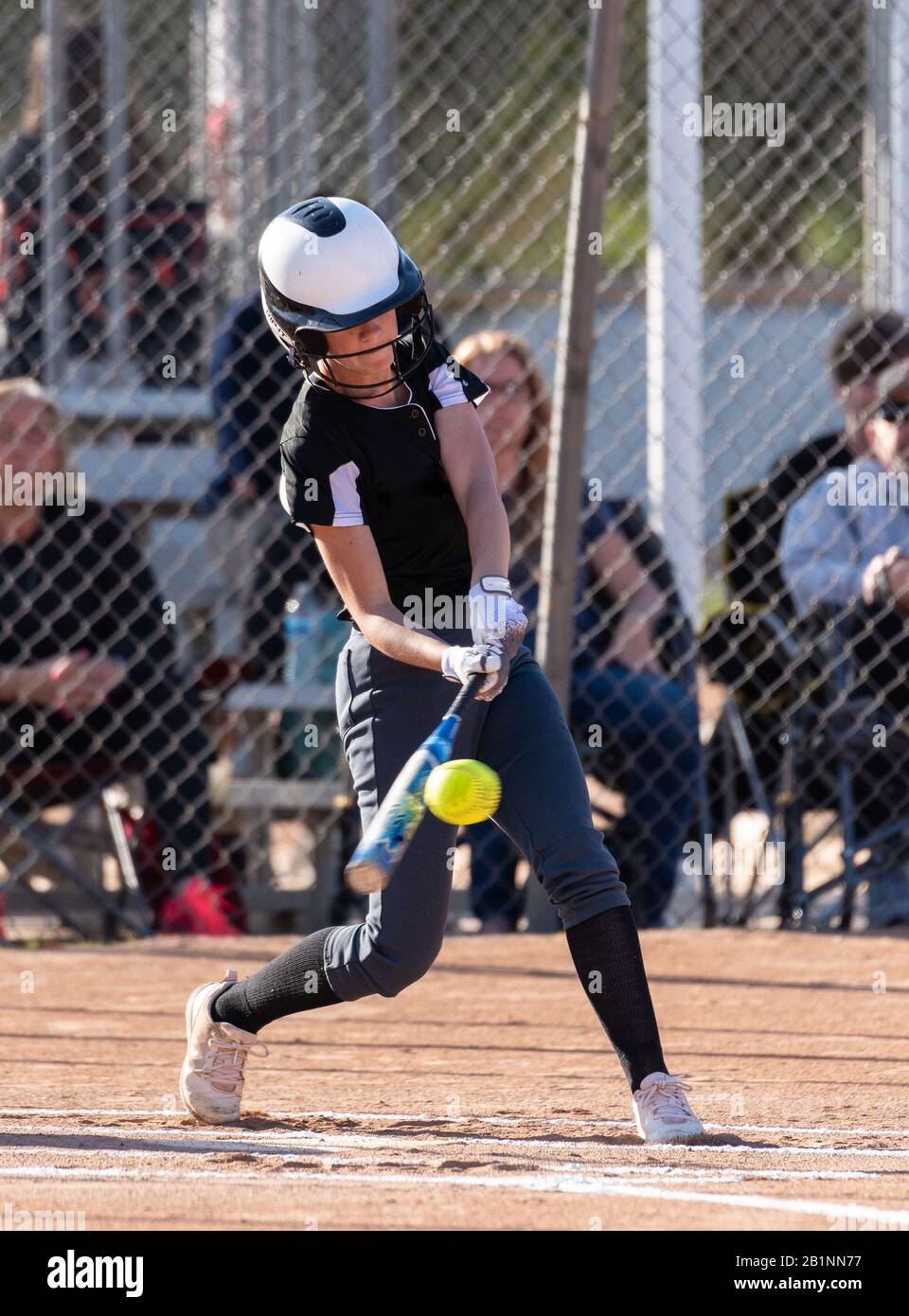 Il giocatore di softball femminile della scuola superiore fa buon contatto mentre tiene il suo occhio sulla sfera. Foto Stock
