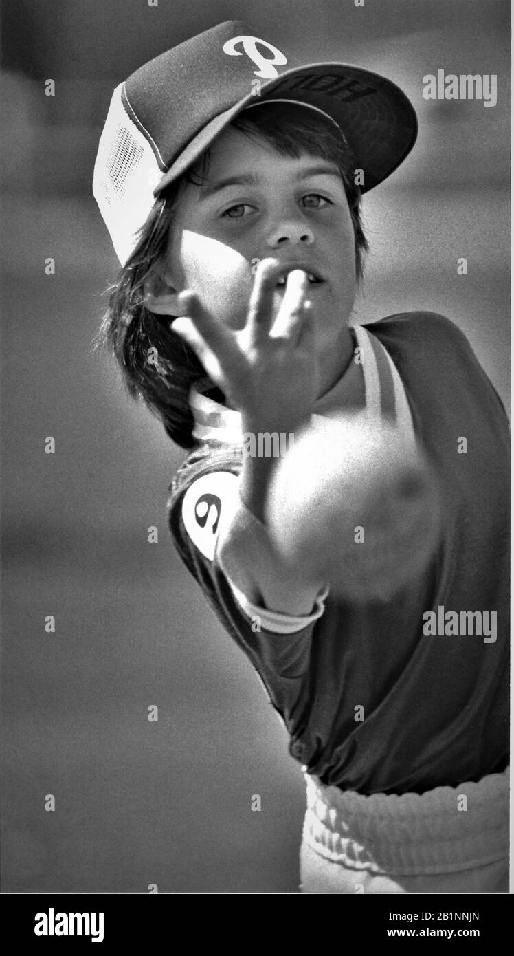 4 ° grado ragazza pitching un softball nel suo gioco per la sua scuola in uniforme e cappello Foto Stock