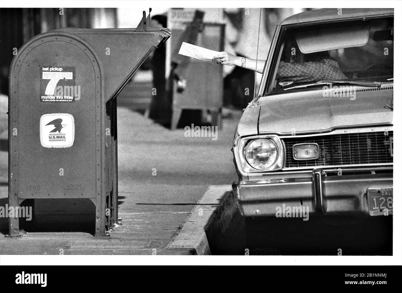 Autista di auto che deposita le dichiarazioni fiscali l'ultimo giorno in una casella postale dell'ufficio postale di USPS al marciapiede, ufficio postale Foto Stock