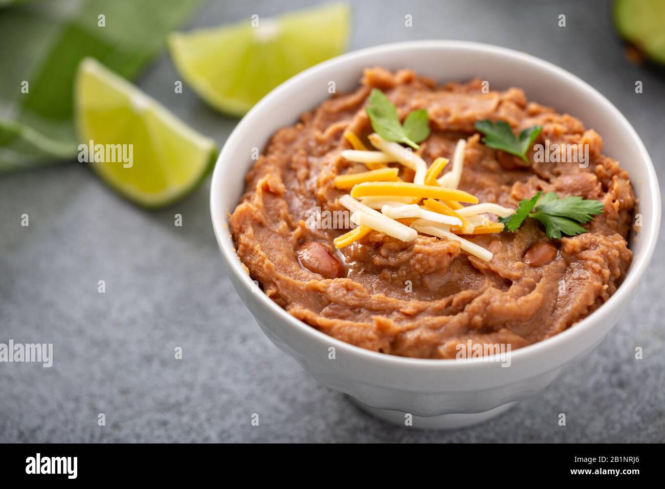 Fagioli refriged in una ciotola bianca Foto Stock