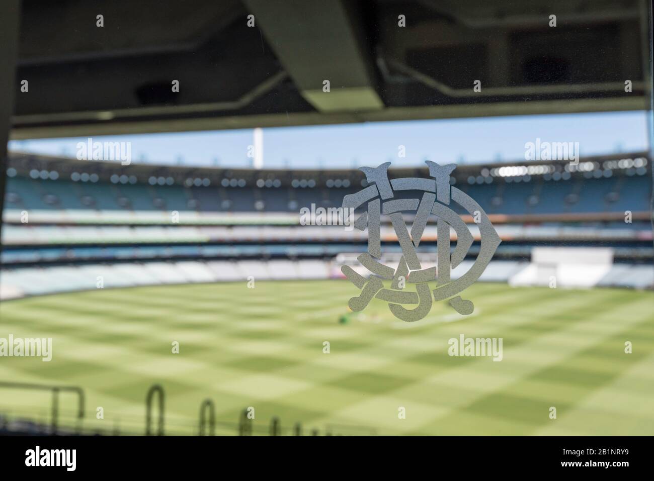 Il logo del Melbourne Cricket Club (MCC) su una porta di vetro nel MCG Members bar con il campo che viene readiato per una partita di cricket sullo sfondo Foto Stock