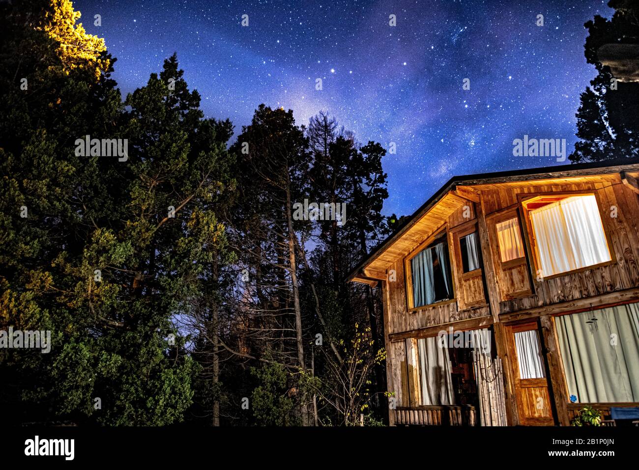 Bariloche, ARGENTINA, 19 GIUGNO 2019: Esterno di una cabina in legno accogliente e rilassante nella foresta con un cielo stellato sorprendente Foto Stock