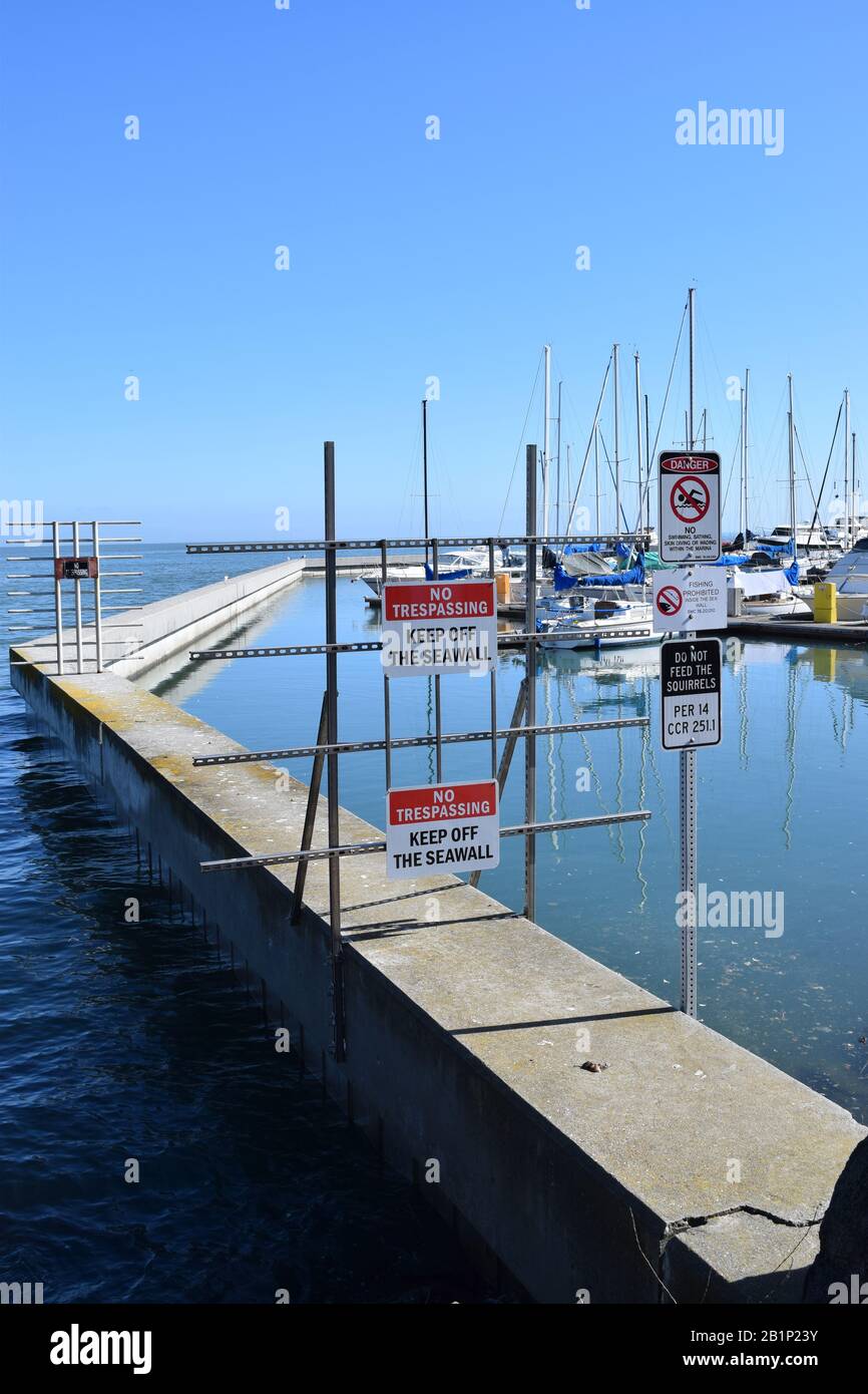 Barriera e segnali di avvertimento che proteggono un muro di banchina e marina. Foto Stock