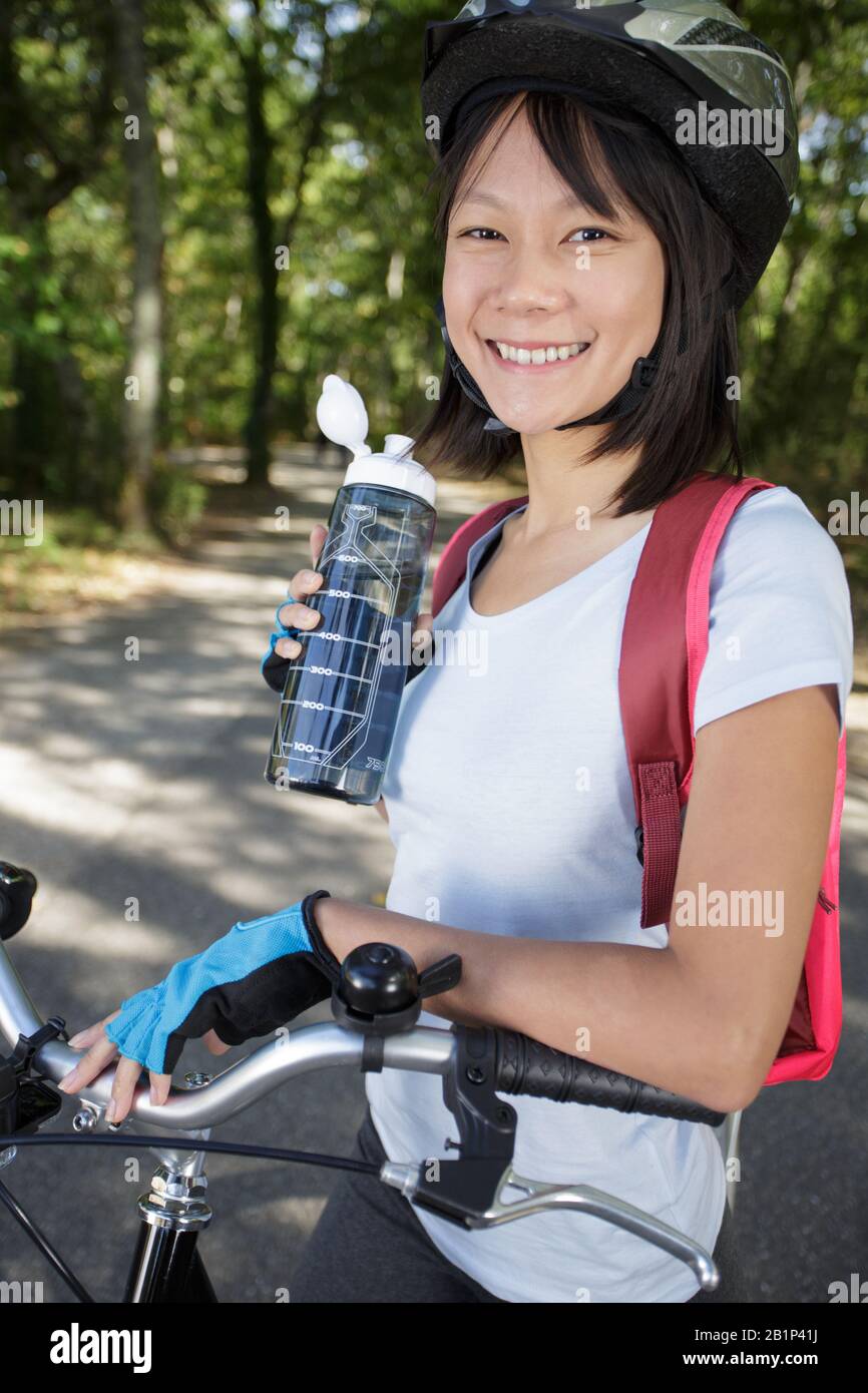 felice giovane donna bere acqua in bicicletta Foto Stock