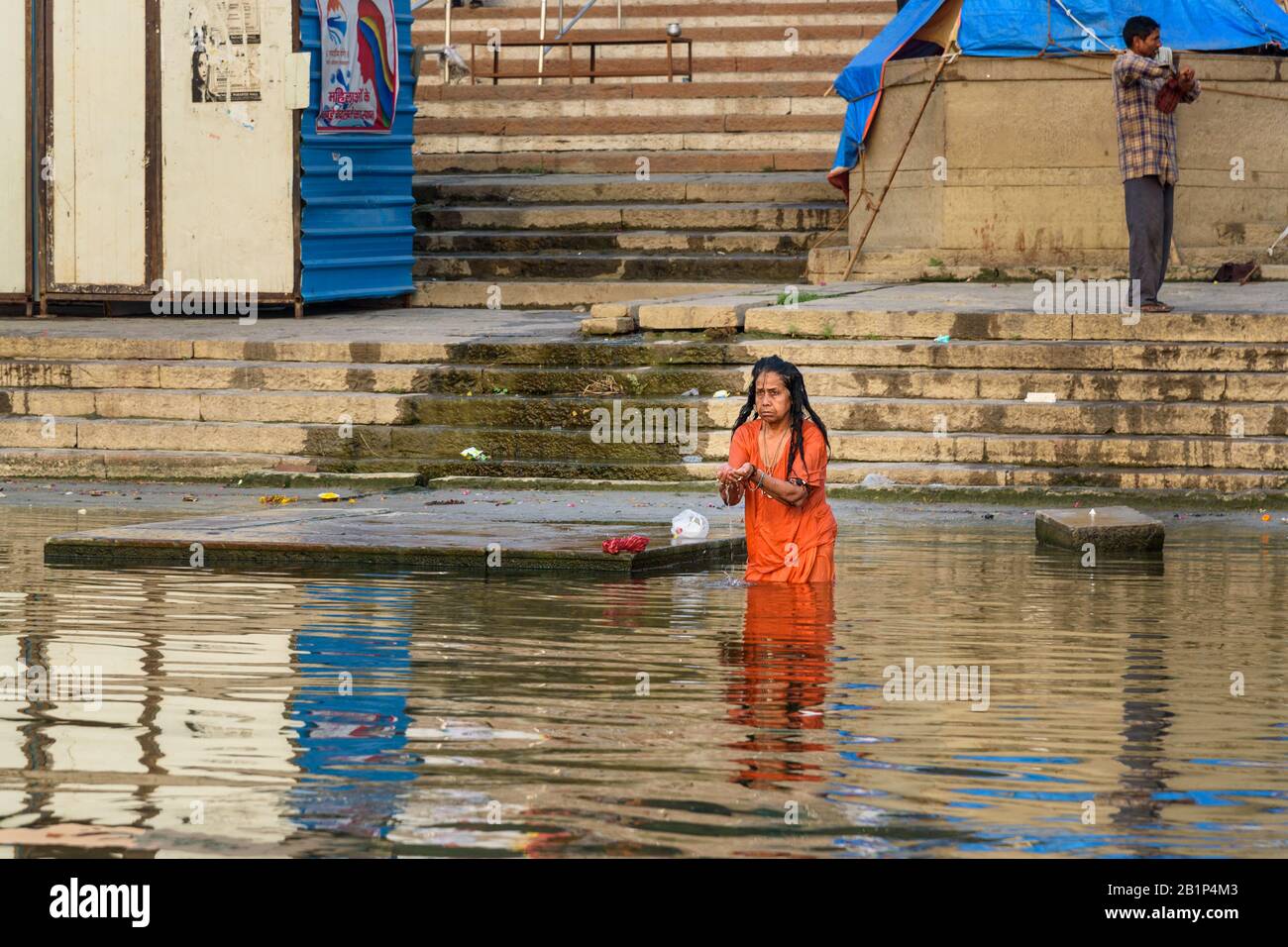 Donna anziana indiana che bagna in acqua Santa Ganga fiume al mattino. Varanasi. India Foto Stock