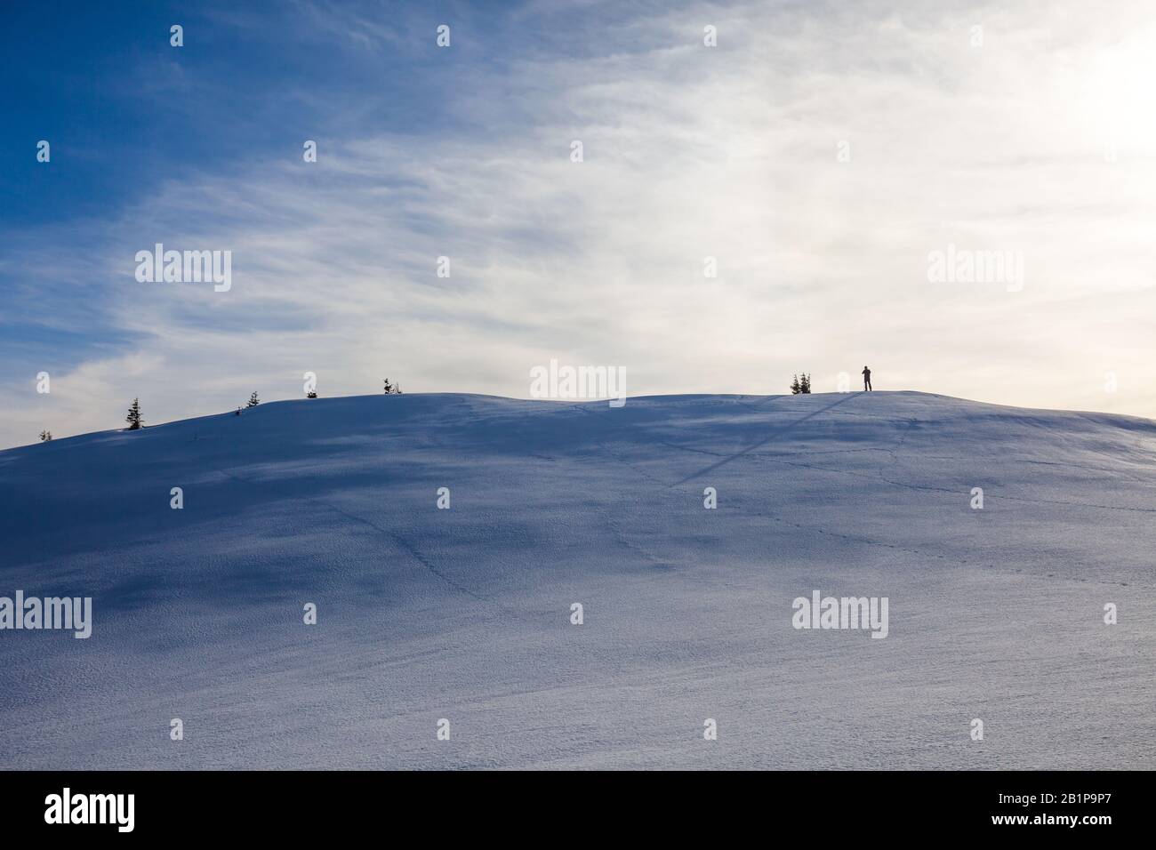 Escursionista con lunga ombra sulla cima del Monte Ciucas in una soleggiata giornata invernale al tramonto, parte della catena dei Carpazi rumeni Foto Stock