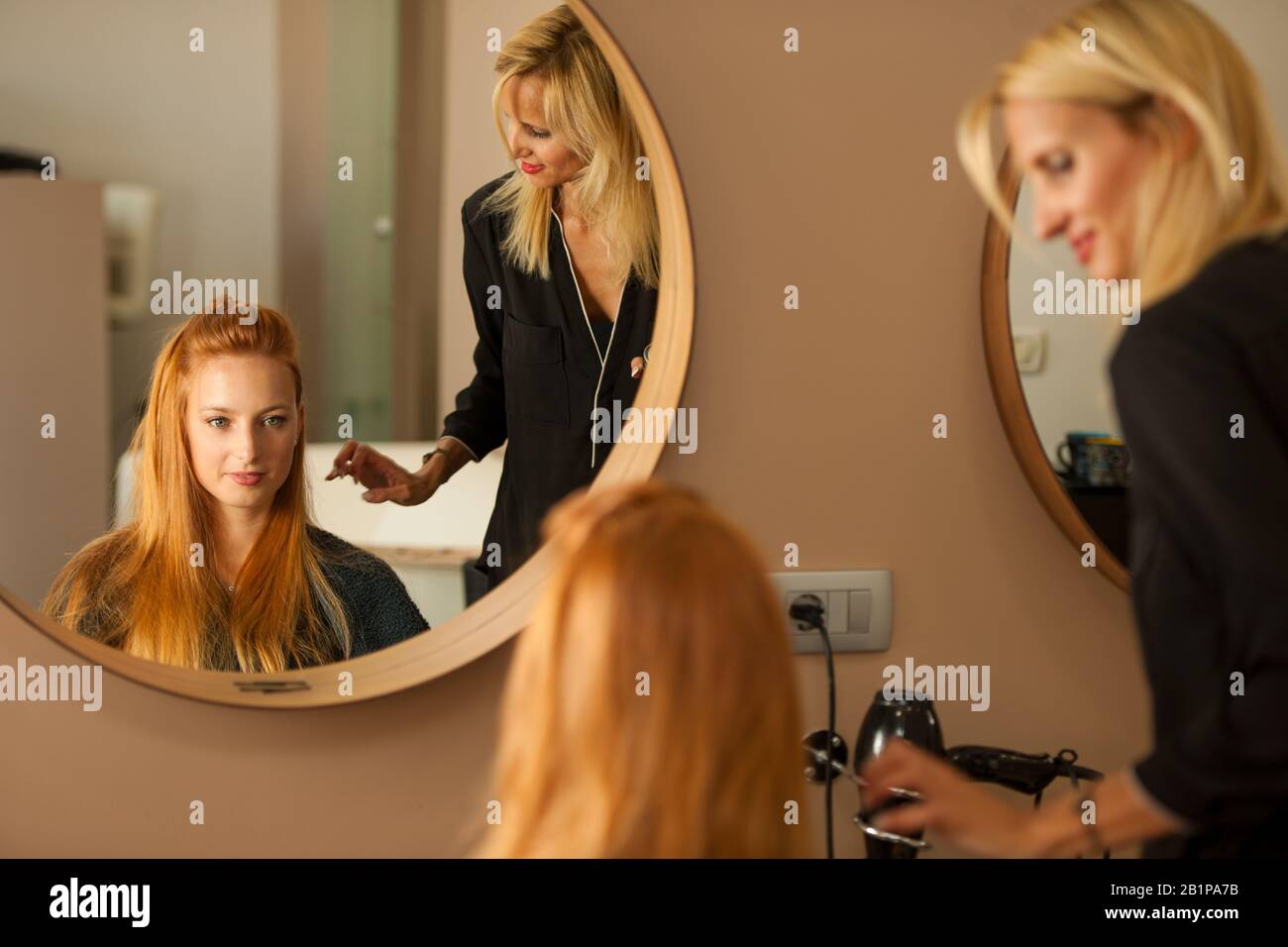 Stylist capelli asciuganti di un cliente femminile al salone di bellezza - hairstylist al lavoro Foto Stock